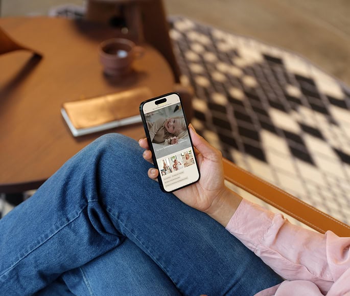 mockuuups woman holding an iphone with maela website